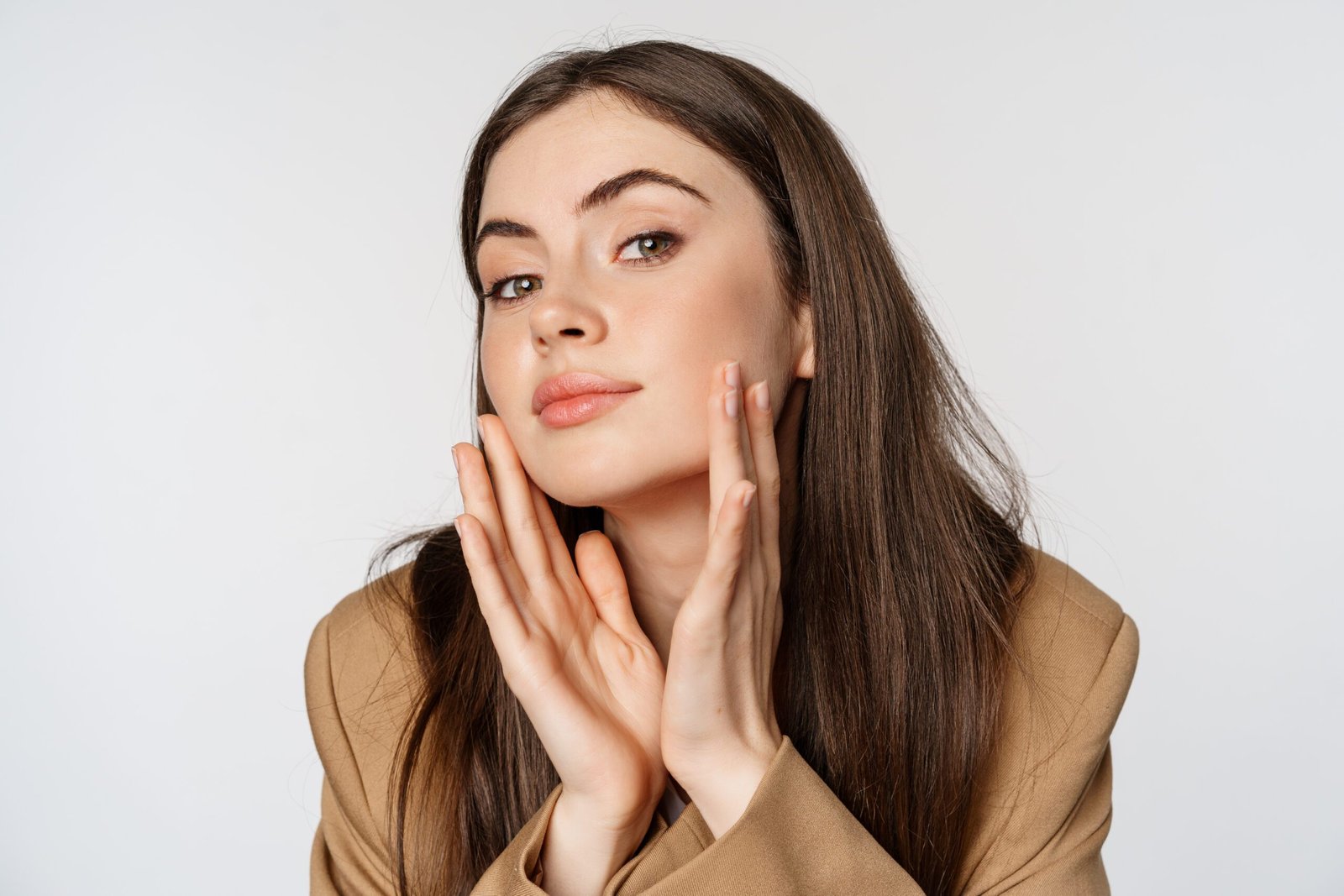 Beauty and skin care. Close up portrait of beautiful woman looking in mirror and touching her clear glowing face, standing over white background